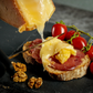 Branza Maturata Raclette Reteta Originala imagine de sus felie de paine cu sunca cu branza topida peste si rosii langa